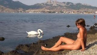 A naked girl is having fun on the riverbank, bringing risk to herself