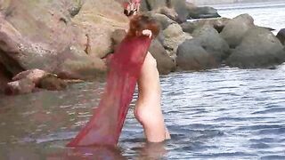 Nudist girl has small boobs and gets them wet in the ocean