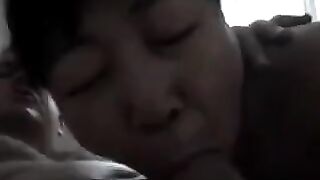 An elderly Chinese woman practices her blowjob skills