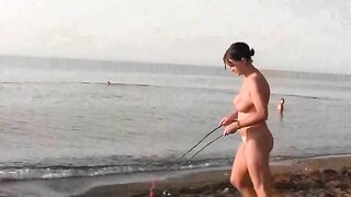 A girl is having fun naked on the sandy coast of the sea