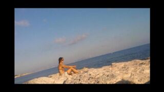 A naked girl is basking in sun on the beach