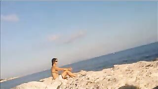 A naked girl is basking in sun on the beach