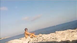 A naked girl is basking in sun on the beach