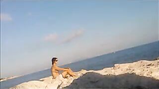 A naked girl is basking in sun on the beach