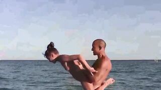 A naked beauty does acrobatics on the beach, showcasing flexibility